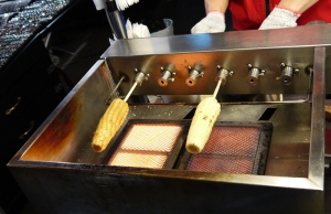 The corn is first boiled and then placed on a rotisserie to achieve that crispy coat.