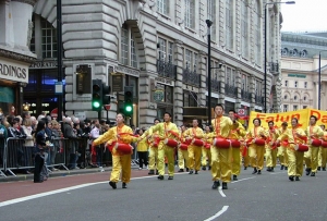 Londons nyårsparad, Ben Chen till höger och andra Falun Gong-utövare spelar midjetrummor tillsammans med hundratals andra grupper som tågar längs Piccadilly.
