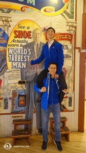 It takes one and a half men, as demonstrated by dancers Kelvin Diao (top) and Tony Xue (bottom), to match heights with the world’s tallest man who stood 8’11” (2.72 meters). His shoes are on display at the Pike Place Market. (Photo by Daren Chou)
