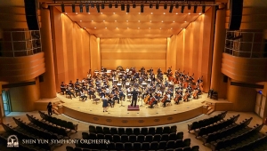 Violin soloist Fiona Zheng and the symphony rehearsing on stage.
