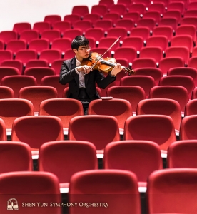 Violist Tongsheng Ye warmt op in een zee van theaterstoelen.
