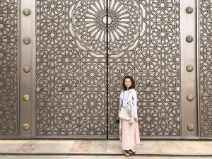 Here she stands in front of an intricately carved set of doors.
