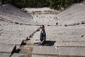 Daniella sitzt im antiken Theater von Epidaurus. Sie findet es toll in einem alten Theater in dem Land zu sein, in dem das Theater erfunden wurde! - hier: Antikes Theater des Epidaurus.
