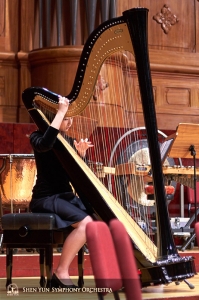 Harfistka Shirley Guo využila čas před koncertem pro ladění strun. 