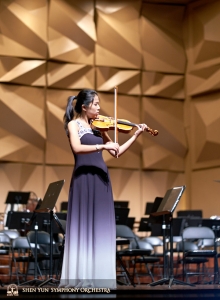 Houslová sólistka Fiona Zheng již převlečená na představení, využívá poslední příležitosti k tréninku na jevišti.