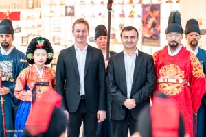 Le premier basson Aleksander Velichko (à gauche) et le tromboniste basse Pavlo Baishev posent avec des coréens parés des vêtements traditionnels des souverains. 
