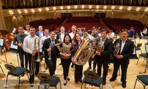 After a great tour, the brass section (plus one) gathers for a group photo—can you spot the non-brass musician?