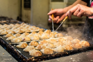 Takoyaki—Osaka's signature street food—octopus dumplings that are shaped and turned with steel pins while cooking.
