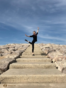 La danseuse Daoyong Zheng pose sur les marches de pierre près de la plage. (Photo de la projectionniste Annie Li)<br />
