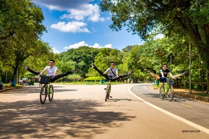 Dancers get in some extra stretching while bike riding.