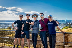 Performers and their choreographer pose in front of a picturesque Auckland view.