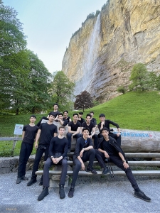 Met de rug naar de watervallen en luisterend naar het geluid van kabbelende beekjes, rust de groep uit aan de voet van de Alpen.