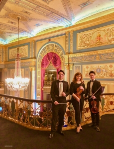 משמאל לימין: יון צ'וּ (מנצח), אסטריד מרטיג (כנרת ראשית), וצה-יו צ'אנג (כינור ראשון) בבית האופרה בדטרויט.