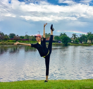 La prima ballerina Elsie Shi accoglie l'avvistamento dell'arcobaleno nello Stato del Sole a braccia aperte e con una punta al cielo.