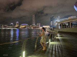 Die Erhu-Virtuosin Linda Wang besichtigt die Marina Bay in Singapur bei Nacht. 