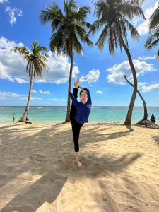 Ondertussen geniet een andere danseres van haar dagelijkse stretchoefeningen in de schaduw van de weelderige palmbomen. 