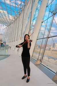 In the expansive lobby, violinist Stella finds a quiet corner to hone her skills.