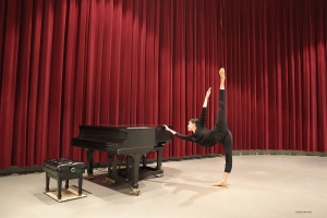 Da keine Pianistin in Sicht ist, steht die Tänzerin Anna Wang im Zentrum der Bühne und verleiht der Szene ihren eigenen Schwung, indem sie mit ihrem Bein in einer überschwänglichen Energieleistung einen Kick ausführt.