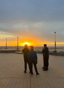 Der Erste Tänzer Kenji Kobayashi und seine Begleiter versuchen ein Foto von der prächtigen Sonnenkugel zu machen, bevor sie in Ostende unter dem Horizont verschwindet.
