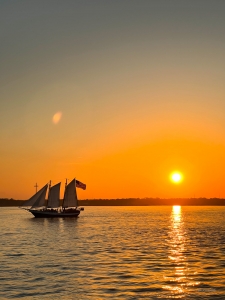 A moment of tranquility as the Florida sun sets on the horizon and a ship sails through calm waters.