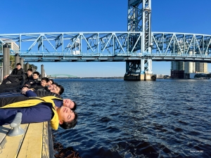 Die Mitglieder der Shen Yun International Company ruhen sich am Wasser aus und genießen die Aussicht unter der geometrischen Main Street Bridge in Jacksonville, Florida.