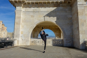 In the picturesque setting of Cagliari's Saint Remy Bastion, Italy, a dancer strikes a graceful pose. This iconic landmark, built in the late 19th century, offers a panoramic view of the Italian city.