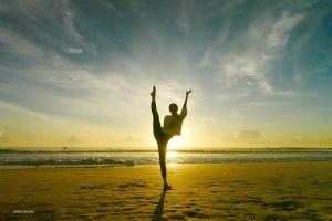 Нежась в золотом сиянии песчаных пляжей Голд-Коста, солистка Анна Хуан изящно вытягивает одну ногу. Её силуэт обрамлён лазурными водами и яркими лучами солнца.