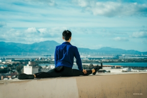 Poised beneath the sky's expanse, a Shen Yun dancer finds harmony in the discipline of his craft, stretching towards perfection as the world unfolds before him.