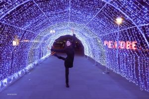 Diterangi oleh kanopi lampu yang berkelap-kelip, penari utama Anna Huang menikmati pesona gerbang yang bersinar ini.