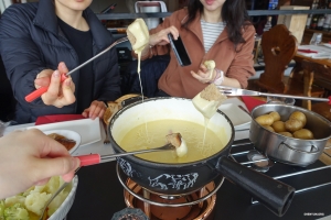 Menikmati tradisi fondue keju Swiss, pemain kami berkumpul di sekitar panci yang mendidih, menikmati setiap gigitan yang lembut dan memanjakan.