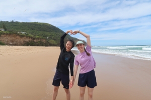 Le ballerine principali Karina Fu e Lillian Parker condividono un momento di spensieratezza, formando un cuore con le braccia, a simboleggiare il loro amore per le spiagge e la gioia delle avventure costiere!