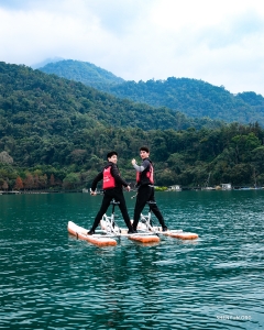 At Taiwan's Sun Moon Lake, dancers admire the placid, blue-green waters surrounded by lush, forested mountains.